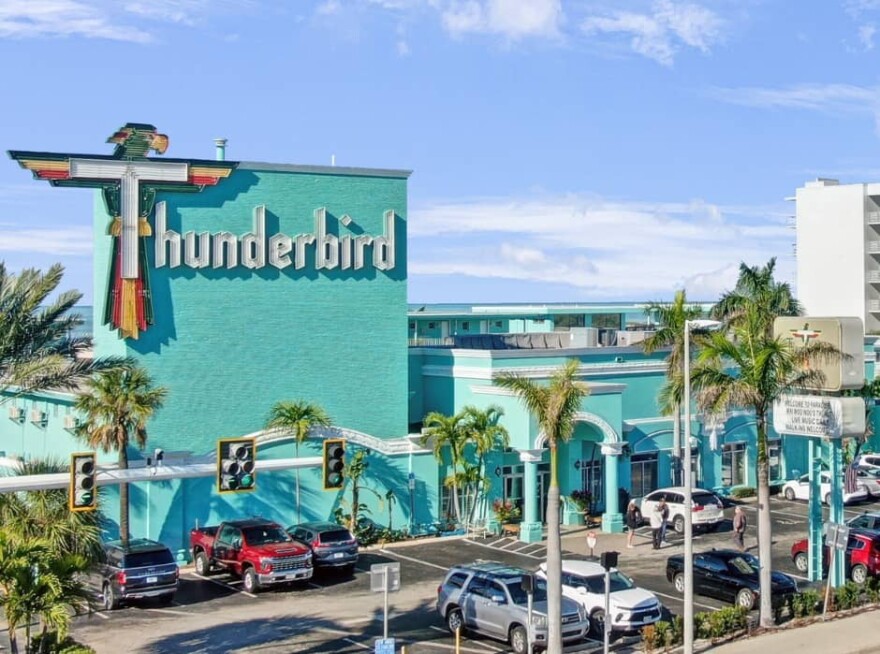 Exterior of a green building that says Thunderbird, with the T in the shape of a bird