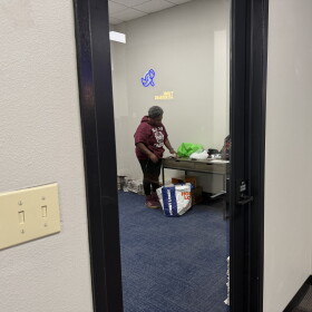 A woman in an almost empty office unpacking newspapers from a bag.