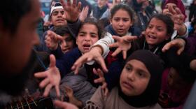 Displaced families extend their hands while waiting for donated food beside the tents they use as shelters after fleeing Israeli bombardment in southern Lebanon, in Beirut, Lebanon, Thursday, April 9, 2026. (Emilio Morenatti/AP)