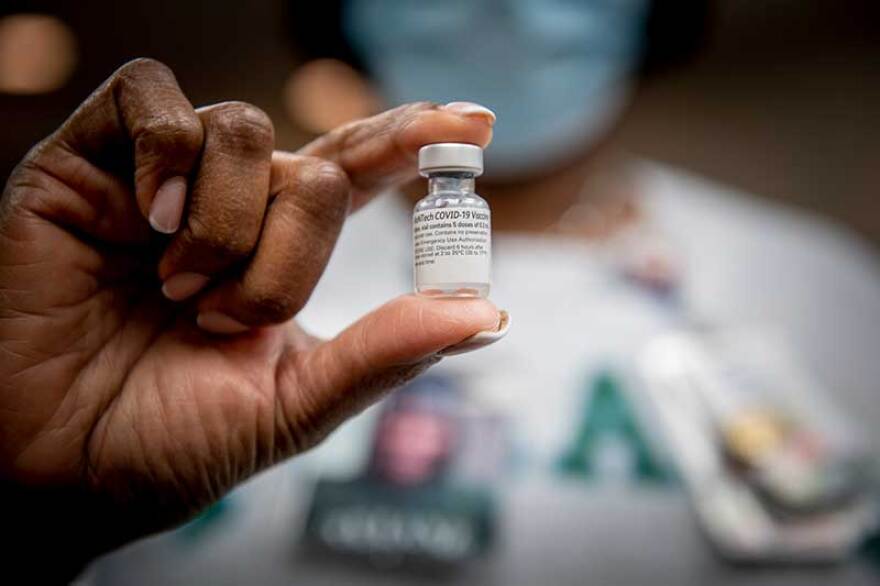 A Tulane University physician holds a bottle of the Pfizer COVID-19 vaccine at a university vaccination event.
