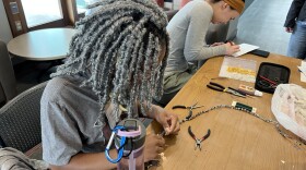 Naomi Restituyo, a RPI freshman, helps fix a necklace for an attendee at the RPI Repair Cafe.