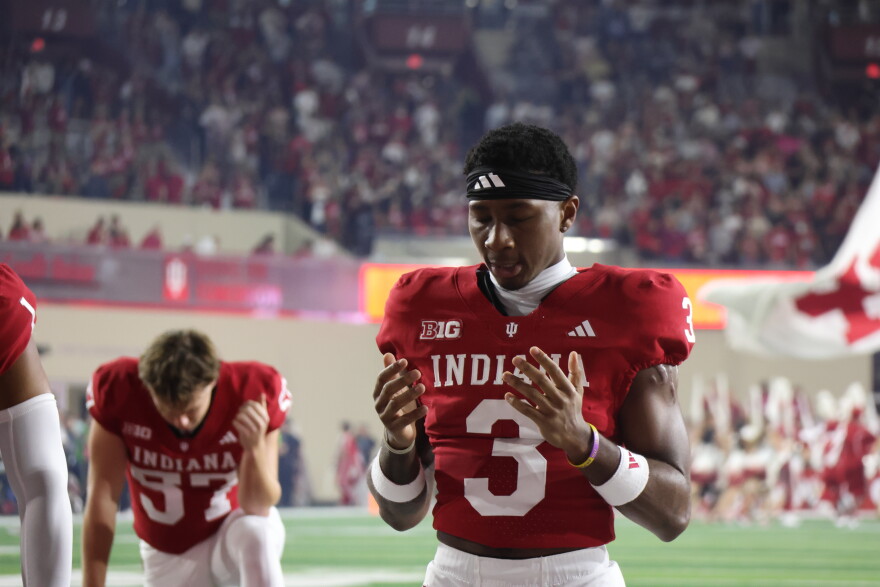 DB Jaylen Bell takes to his knees and prays in the end zone before a night game at memorial stadium. His teammates surround him in prayers of their own.