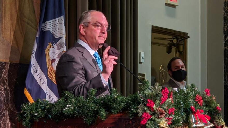 Louisiana Gov. John Bel Edwards holds up his mask as he addresses members of the press. Dec. 31, 2020.