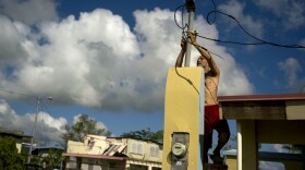 In October 2017, a resident tries to connect electrical lines downed by Hurricane Maria in Toa Baja. Puerto Rican officials say electricity has returned to all residents without it after the hurricane.