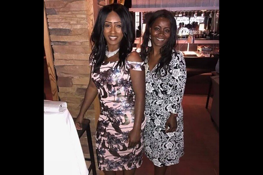 A photo of two Black women, Maranda Mills and her mom Kimberly Phillips, posing for a photo in formal, black-and-white floral dresses. They stand close together smiling for the camera.