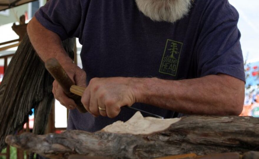 Kendall Thurston, 63-year-old owner of Phoenix Woodworks, chips away wood shavings to reveal the partially complete face of a gnome. The gnome, which he estimated takes 30 hours to complete, is for his son and serves as a woodworking demonstration.