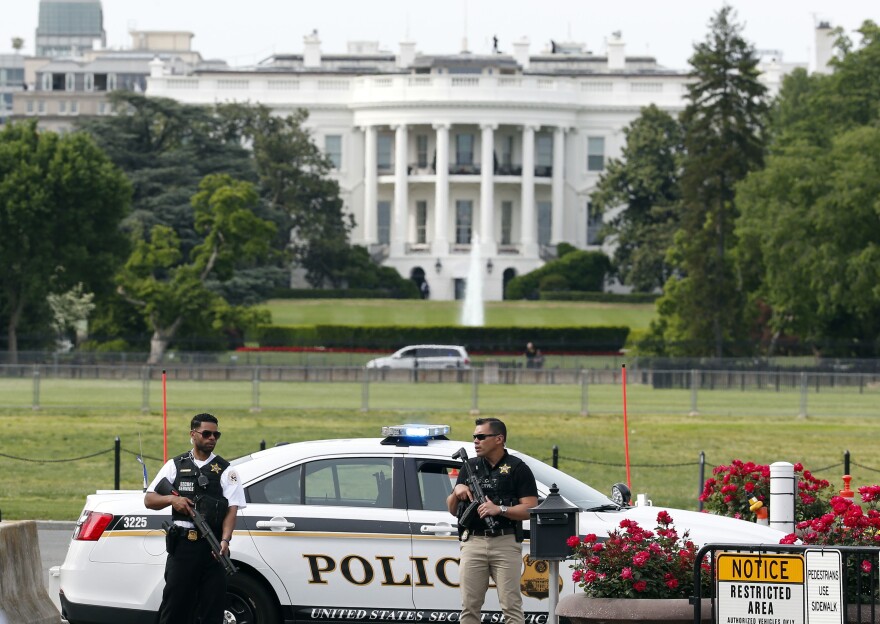 Law enforcement personnel stand south of the White House on Constitution Ave., in Washington, D.C., on Friday,. The White House was placed on a security alert after a Secret Service officer shot a man brandishing a firearm near a security checkpoint on a street outside the White House.