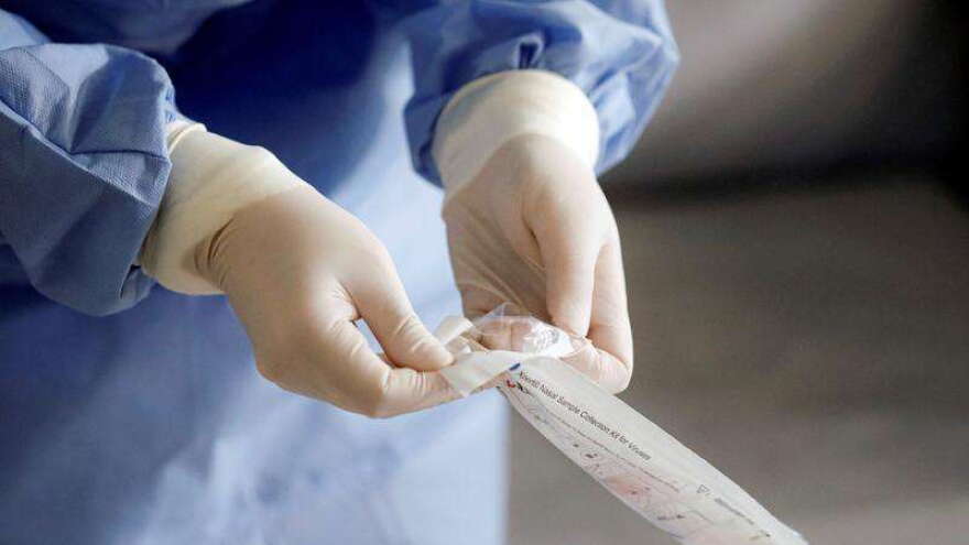 A health official prepares to take samples for a coronavirus test from a journalist in Bucharest, Romania, Friday, March 13, 2020 after it was confirmed that a senator who attended several meetings in the building tested positive for the infection.(AP Photo/George Calin)