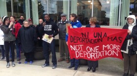 Speakers hold signs and stand in front of Bloomington City Hall