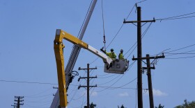 FILE - Linemen work on poles, Aug. 13, 2023, in Lahaina, Hawaiʻi, following the deadly wildfire.