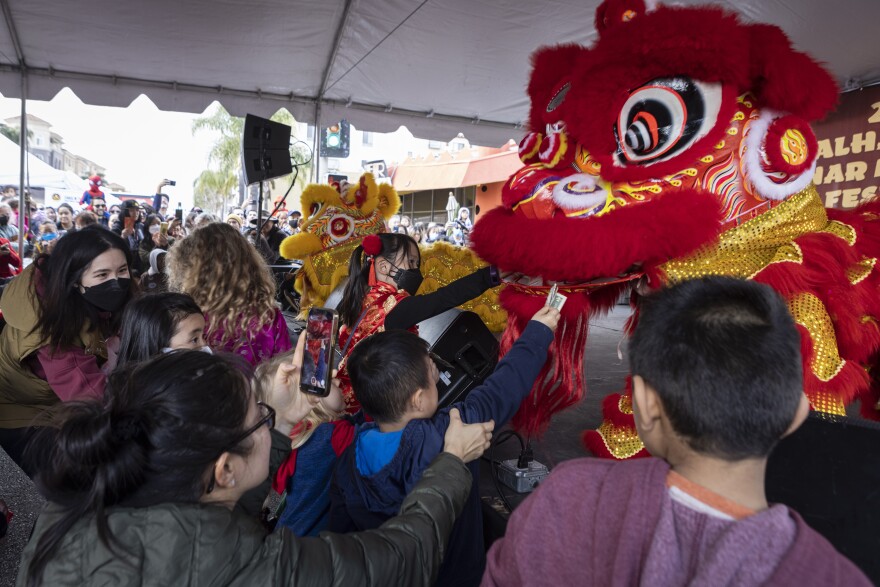 Children feed red envelopes and money to a red dragon during this year's Alhambra Lunar New Year Festival in Alhambra, Calif.