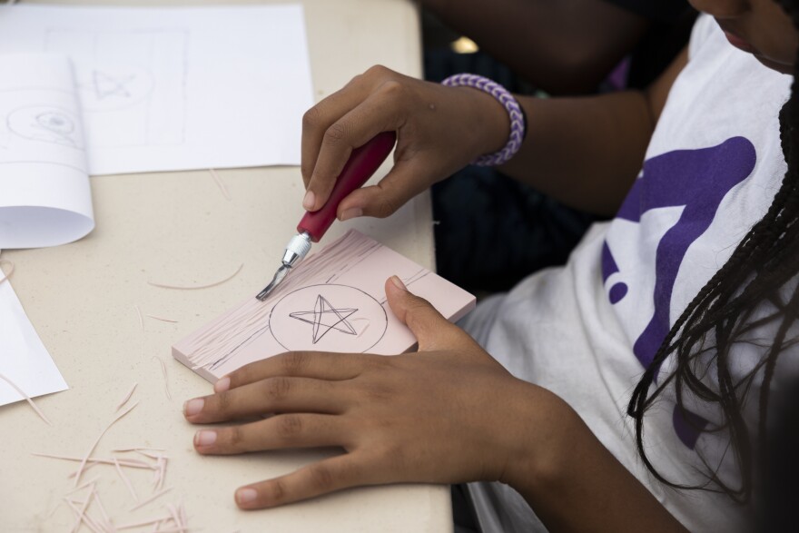 In an art activity, Tewa carves an Ethiopian flag: the country she was born in.