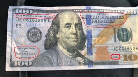 An annotated $100 movie prop bill outlining identifying markings that declare it as such.