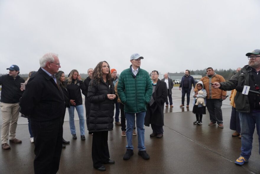 A group of people stand on pavement on a cloudy day.