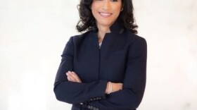 Adrienne Harris is a navy suit with her arms folded