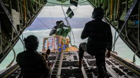 From left, U.S. Air Force Senior Airmen Mark Weinstein and Cody Raymond, 374th Air Expeditionary Wing loadmasters, drop humanitarian bundles during an airdrop as part of Operation Christmas Drop 2025 at the Federated States of Micronesia, Guam, Dec. 10, 2025.