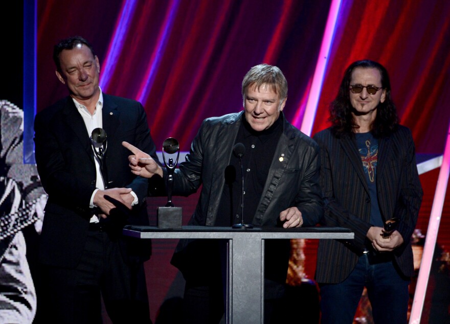 Alex Lifeson (center) with Neal Peart (left) and Geddy Lee at Rush's 2013 induction into the Rock and Roll Hall of Fame.