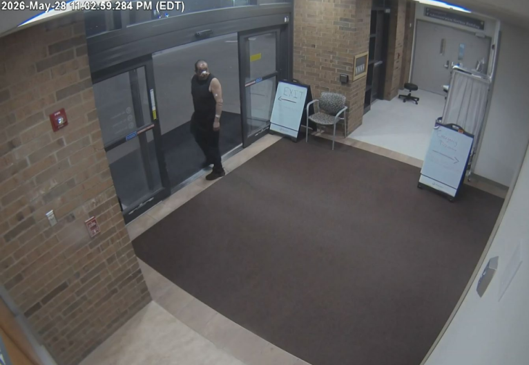 A man with bandages on his face wearing a black tank top is seen looking back while exiting Trinity Health Hospital in Ann Arbor, Michigan.