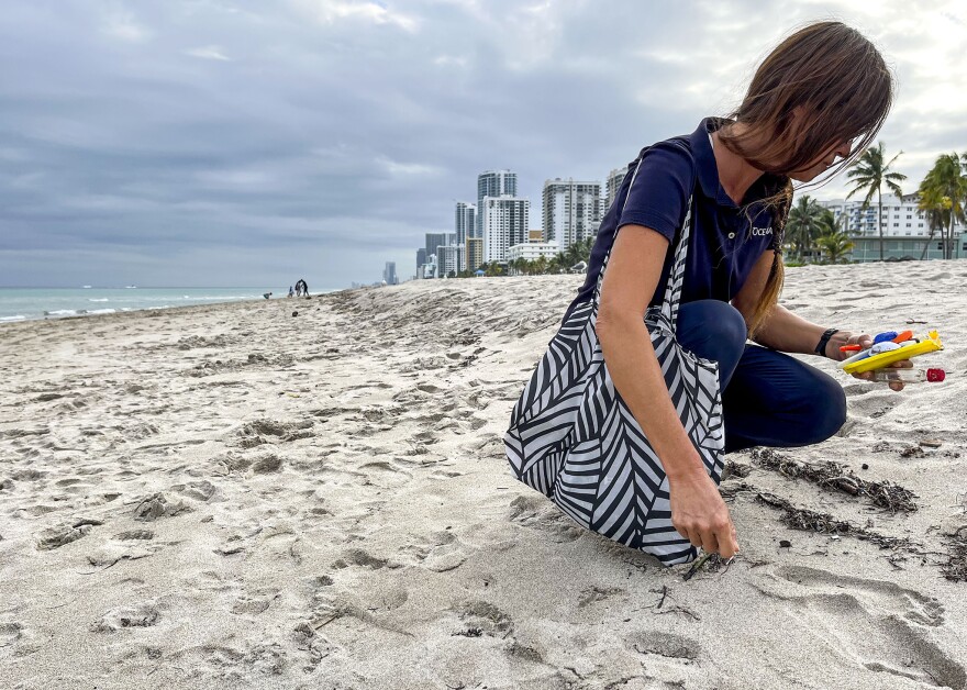 Getting down to her knees, Catherine Uden adds more plastic to the collection of materials occupying her left hand.