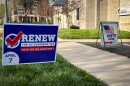 A blue sign with white and red lettering reads "Renew the KC earnings tax. Vote yes on question 1." Another in the background says "vote here"