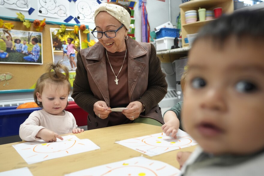 Volunteer Victoria Vasquez, 70, of Providence, R.I., center, supervises one-and-a-half year olds Scarlett Thomas, left, and Liam Echevarria Gaytan, right, in an early childcare program in Providence, R.I.
