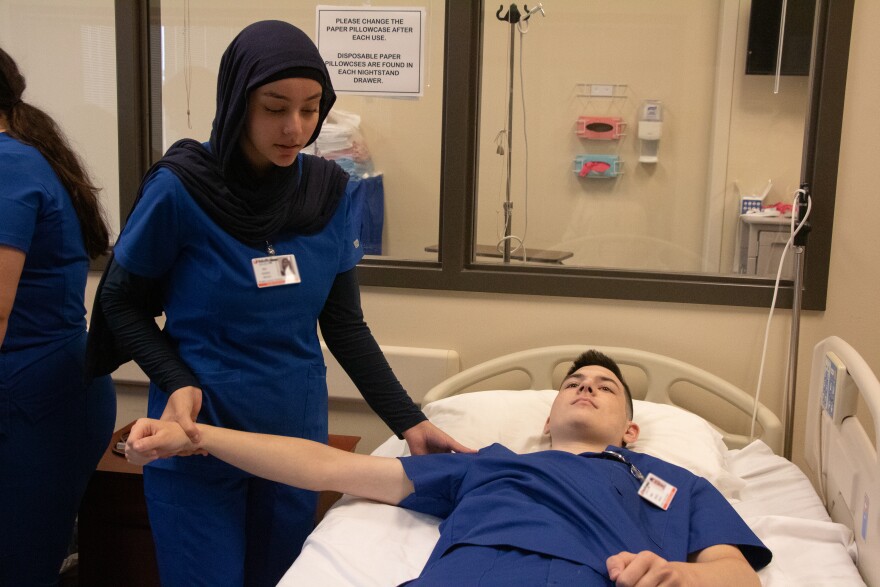 Tulsa Tech Nursing Transitions student Aya practices range of motion exercises on one of her classmates.
