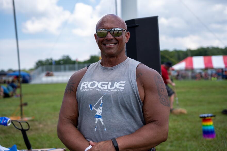 Muscular man smiles at camera.