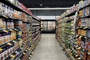 Two shelves are lined to the edge with canned goods, leading down an aisle to coolers at Gettysburg Grocery