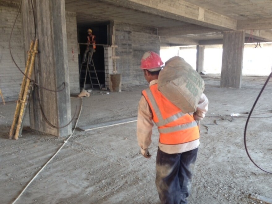 A worker carries a bag of cement for construction of a hospital in Gaza City in early October. This project, funded by Qatar, brought in cement from Egypt, with the excess given to the Hamas government. Since the end of this summer's war, the Qatari projects have been relying on the local black market for cement.