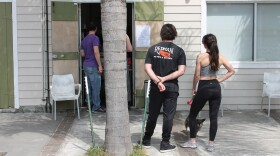 Customers wait outside a walk-up window at The Orange Couch in New Orleans. March 19, 2020.