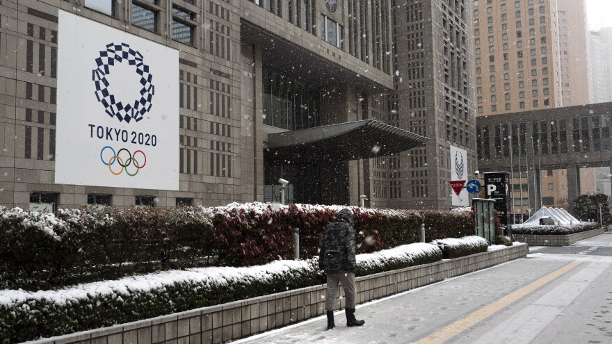 The International Olympic Committee has set firm dates for the delayed Tokyo 2020 Olympics, which are now set to start in July 2021. Here, a man walks past a banner promoting the Tokyo 2020 Olympics on Sunday, after a late-season snow in Tokyo.