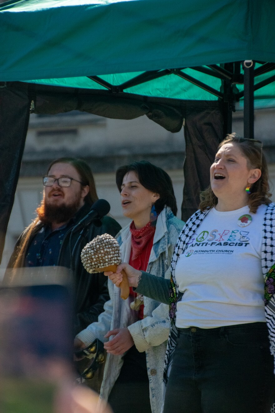 Sara Offner-Seals is joined on stage by two members from Fort Wayne's singing resistance group as they lead the crowd in a protest song on Saturday. Offner-Seals says singing resistance groups have been cropping up across the country and offer people connection and a bit of joy to avoid protest burnout.