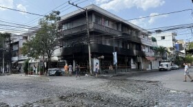 A handful of residents walk cobblestone intersection in front of a partially burned down OXXO convenience store, similar to 7-11 in the U.S., located on the corner of a street in Puerto Vallarta, Mexico. 