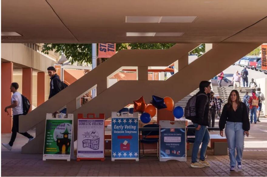 Students walk past signs promoting early voting at the University of Texas at El Paso on Tuesday.