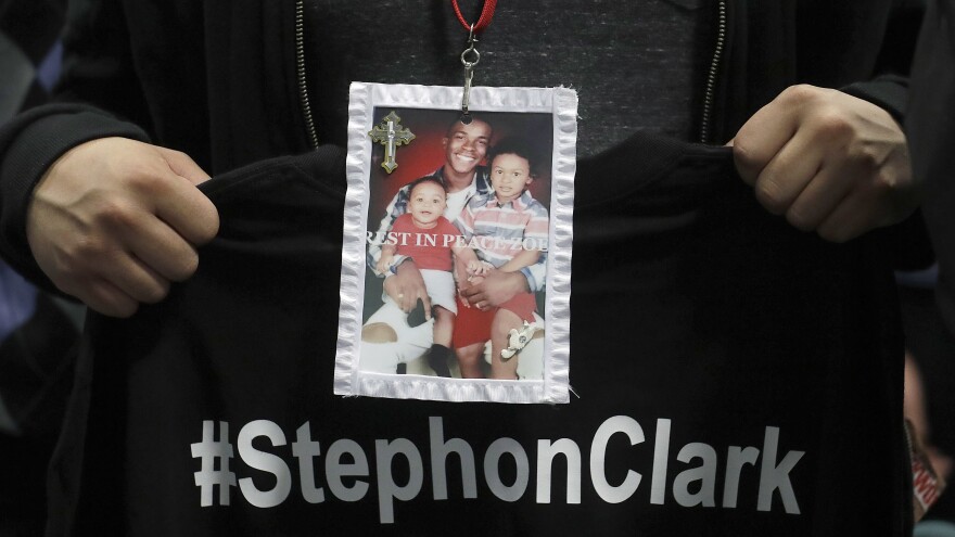 A mourner displays a photo of Stephon Clark during his funeral services Thursday.