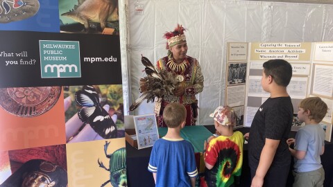 James Flores, tribal liaison at the Milwaukee Public Museum, is dressed in traditional Indigenous regalia and explains to students parts of his outfit.