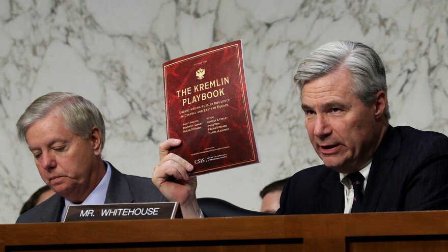 Senate Judiciary Committee member Sen. Sheldon Whitehouse, D-R.I., holds up a copy of The Kremlin Playbook while delivering remarks with Sen. Lindsey Graham, R-S.C., (left) at the conclusion of a subcommittee hearing on Russian interference in the 2016 election on May 8, 2017.