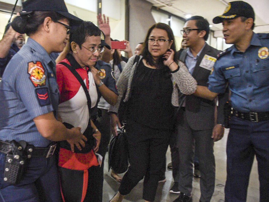 In this photo released by Rappler, CEO and Executive Editor Maria Ressa, second from left, is escorted by police after being arrested upon her arrival at Manila's International Airport on Friday.