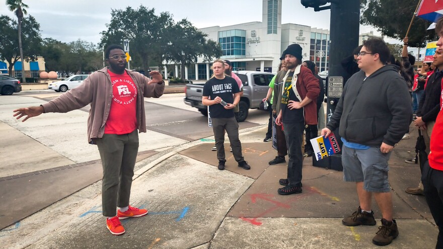 Caleb Pierre (left) speaks to fellow protestors on Saturday, when about 40 people marched through Mills 50 in protest of Maduro’s capture.