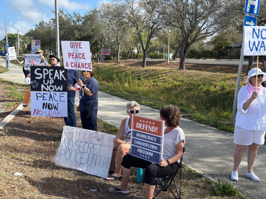 About a dozen people stood along US 41 near Daniels Parkway Saturday to protest US war activity in Iran.