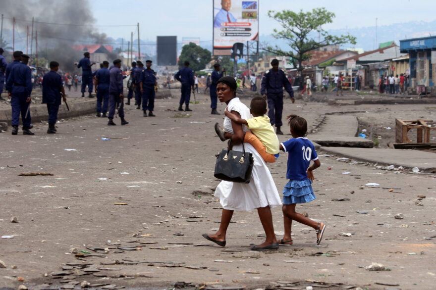 A family pass near Congolese riot police during a protest in Kinshasa, Democratic Republic of Congo, Monday, Sept. 19, 2016. (John Bompengo/AP)