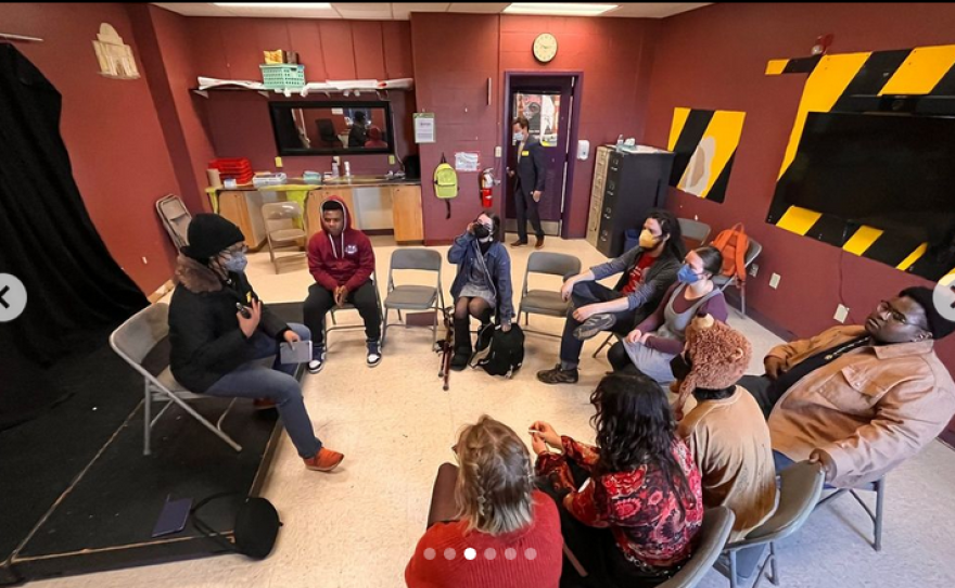  A classroom full of people seated on folding chairs in a circle