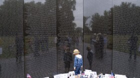 A child reads names etched on the wall at the Vietnam Veterans Memorial, ahead of Memorial Day in Washington, Sunday, May 28, 2023. (AP Photo/Jose Luis Magana)