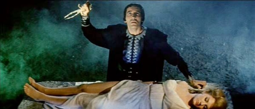 Screenshot from the 1961 cult film 'Hercules in the Haunted World' showing a male character hovering over a woman laying on a slab 