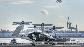 An electric vertical takeoff and landing (eVTOL) aircraft flies above the Joby eVTOL aircraft during a demonstration of eVTOLs Nov. 13, 2023, in New York. 