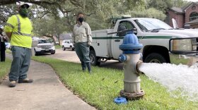 City workers watch as they test water flowing from a city hydrant.