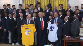 President Donald Trump Stands between LSU Tigers Head Coach Jay Johnson (left) and LSU Shreveport Pilots Head Coach Brad Neffendorf (right) as they each held up a #47 team jersey as a gift for the 47th President of the United States. The event honored both LSU and LSUS baseball teams on Monday, October 20, 2025, in the East Room of the White House.