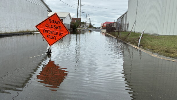 A flooded street with a "road closed" sign