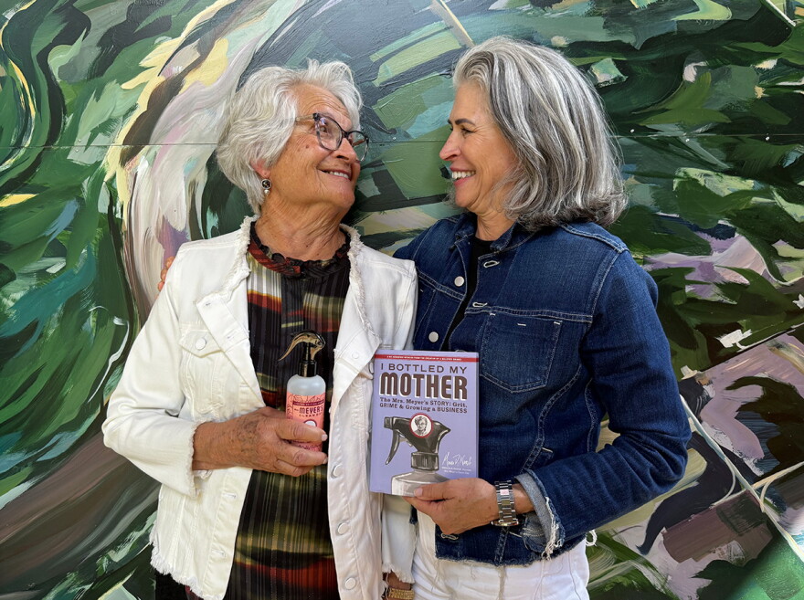 Thelma Meyer holds up a Mrs. Meyer's cleaning product, while Monica Nassif holds up her memoir about founding the business.