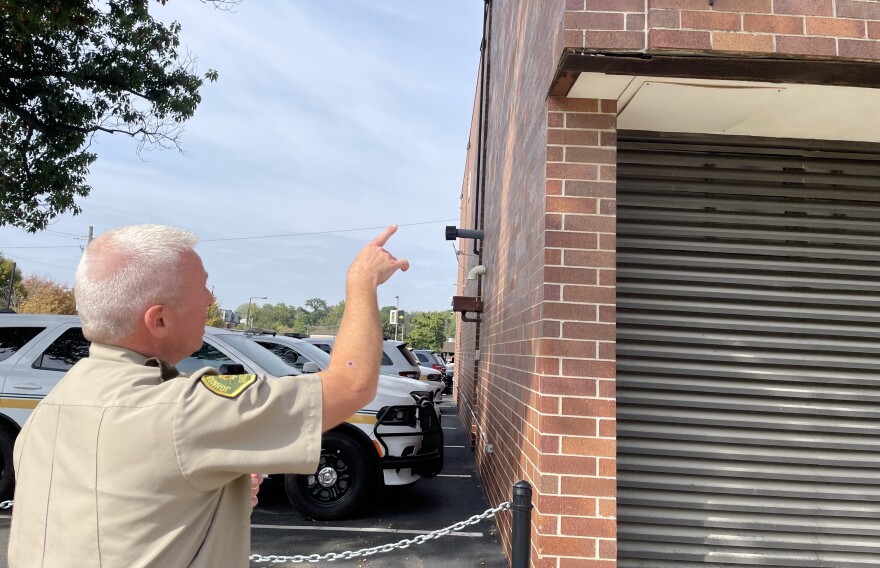A sheriff points to a brick building where it is damaged.